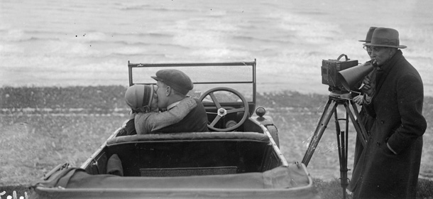 A couple in an open car locked in a passionate embrace for a scene in the film, The Thrill, being shot on Brighton beach. (Photo by Fox Photos/Getty Images)
