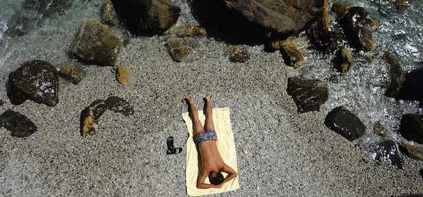 A vacationer sunbathes at a public beach near Santa Margherita Ligure, southern Genova, on Agust 11, 2011. The high-peak tourism season has been slightly affected by Italy's recent economic woes. AFP PHOTO / OLIVIER MORIN (Photo credit should read OLIVIER MORIN/AFP/Getty Images)