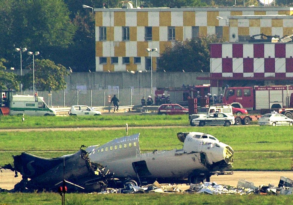 Il deposito bagagli dell'aeroporto di Linate, dietro l'aereo di linea della Sas, in primo piano, dopo l'incidente dell'8 ottobre 2001 (AP Photo/Luca Bruno)