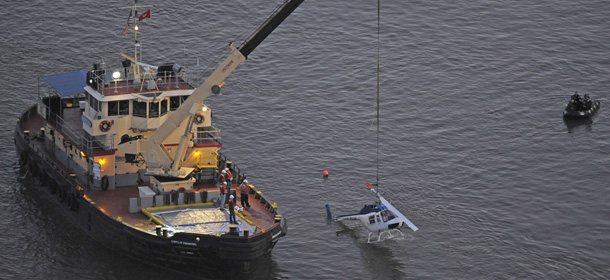 A helicopter that crashed into the East River in New York is raised from the water Tuesday, Oct. 4, 2011. The helicopter with five people aboard crashed into the river Tuesday afternoon after taking off from a launch pad on the riverbank, killing one passenger and injuring three others. (AP Photo/Louis Lanzano)
