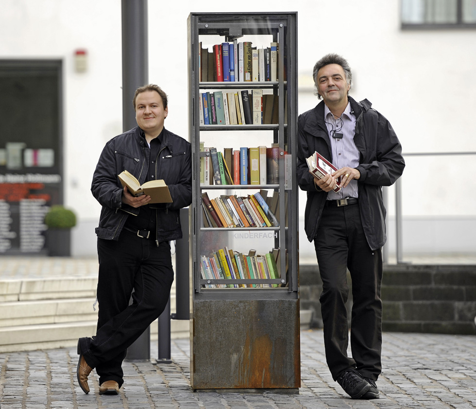 Michael Aubermann e Stephan Schilling, due degli organizzatori del libero scambio di libri a Colonia, inaugurano l&#8217;ultimo dei cinque scaffali sparsi nella città (AP Photo/Martin Meissner)
