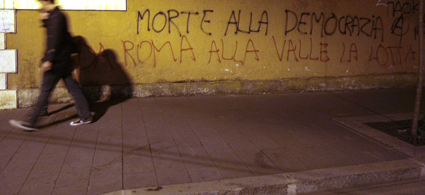 In this picture taken Saturday, Oct. 15, 2011, people walk past murals following clashes between policemen and protesters during a protest against Belrusconi&#8217;s Government austerity package, in Rome. (AP Photo/Gregorio Borgia)
