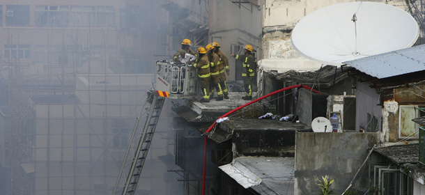 A man stands on a rescue ladder after being rescued by firefighters on a roof top at the fire scene in Hong Kong Wednesday, Nov. 30, 2011. At least nine people died from the fire that ripped through buildings in Mong Kok, a popular shopping destination, which is located in one of the most densely-populated areas in Kowloon, across the harbor from Hong Kong island, local authorities said. (AP Photo) HONG KONG OUT
