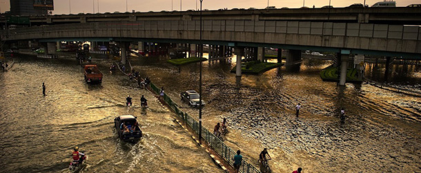 Traffic drives through the flooded streets in Lat Phrao shopping and business district in Bangkok on November 5, 2011. Hundreds of thousands of people have been told to evacuate a number of Bangkok districts but many have chosen to stay despite risks including electrocution, disease and lack of food and drinking water. AFP PHOTO/ Nicolas ASFOURI (Photo credit should read NICOLAS ASFOURI/AFP/Getty Images)
