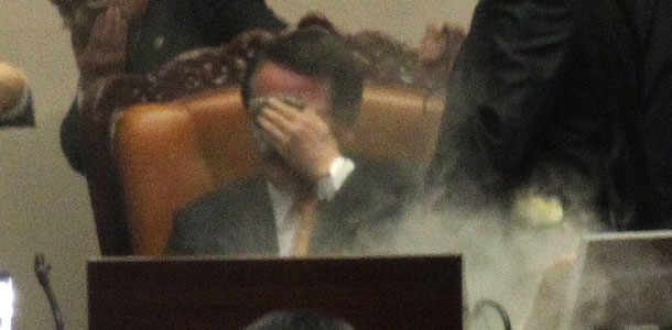 Rep. Kim Seon-dong of the opposition Democratic Labor Party, center bottom, is blocked by security as National Assembly Vice Speaker Chung Eui-hwa, top center, covers his face, after exploding tear gas to try to block the passage of a bill on ratification of a Korea-U.S. free trade agreement at the National Assembly in Seoul, South Korea, Tuesday, Nov. 22, 2011. South Korea&#8217;s parliament ratified a long-stalled free trade deal with the United States on Tuesday after ruling party lawmakers forced a vote amid shouts and shoves from opposition rivals. (AP Photo/Yonhap, Chun Soo-young) KOREA OUT
