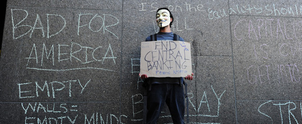 An Occupy LA protestor stands against a wall outside a Bank of America branch covered in anti-big business slogans during a march through the downtown Los Angeles financial district on &#8220;Bank Transfer Day,&#8221; November 5, 2011. Bank Transfer Day, created by the Occupy movement, is a national effort to get people to move their money from large corporate banks into smaller banks or credit unions. AFP PHOTO / Robyn Beck (Photo credit should read ROBYN BECK/AFP/Getty Images)
