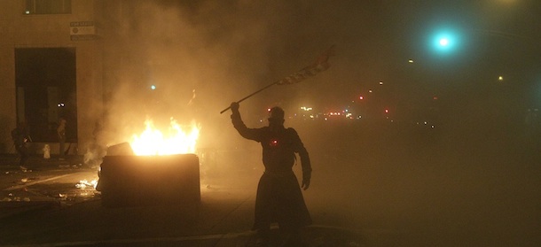 An Occupy Oakland protester waves a flag next to a bonfire as Oakland Police fire chemical agents in Oakland, Calif., Thursday, Nov. 3, 2011. (AP Photo/Jeff Chiu)
