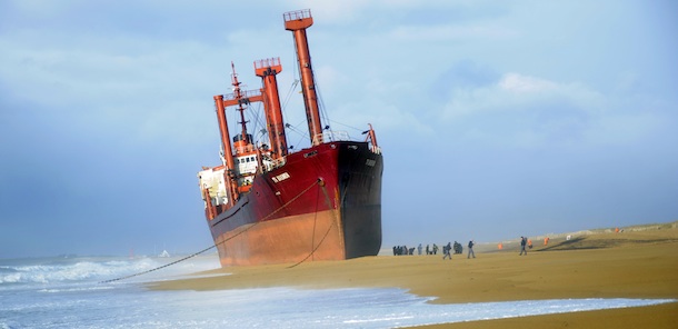Rescue members stand next to TK Bremen cargo ship which ran aground, spilling oil off the coast of France&#8217;s northwestern region of Brittany and lies stranded on Kerminihy beach in Erdeven on December 16, 2011. An oil slick was reported to be floating toward the coast between the city of Lorient and the Quiberon peninsula, according to the Brest maritime authorities. The storm has left nearly 400,000 households without electricity and wreacked havoc on train traffic in Brittany and the Pays de la Loire region due to debris falling on tracks, according to regional authorities and the SNCF rail operator. AFP PHOTO DAMIEN MEYER (Photo credit should read DAMIEN MEYER/AFP/Getty Images)
