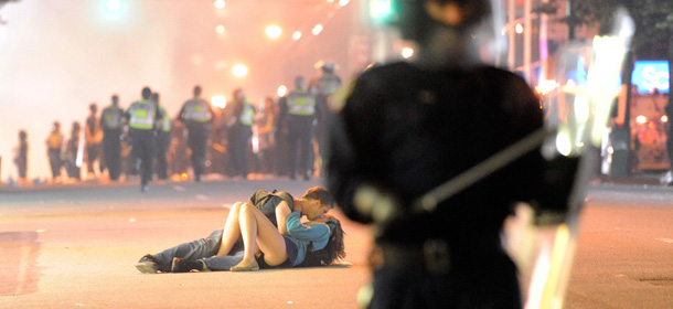 VANCOUVER, BC &#8211; JUNE 15: Riot police walk in the street as a couple kiss on June 15, 2011 in Vancouver, Canada. Vancouver broke out in riots after their hockey team the Vancouver Canucks lost in Game Seven of the Stanley Cup Finals. (Photo by Rich Lam/Getty Images)
