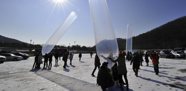 Members of the North Korea peace organization release balloons attached to boxes containing socks and leaflets to be flown over North Korea, at a unification park in the northern city of Paju near the Demilitarized Zone (DMZ) dividing the two Koreas on December 24, 2011. The group sent winter socks slung under the gas-filled balloons across the border to North Korea, a place where one can exchange a pair of socks for a fair amount of food. AFP PHOTO/JUNG YEON-JE (Photo credit should read JUNG YEON-JE/AFP/Getty Images)
