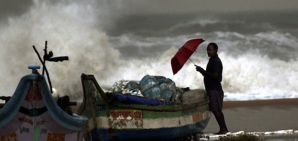 An Indian fisherman stands near boats on the shore as waves break on the Bay of Bengal coast in Chennai, India, Thursday, Dec. 29, 2011. Tropical Cyclone Thane, located in the Bay of Bengal, is forecast to make landfall on the southern coast of India, south of Chennai near Puducherry, early Friday morning. The cyclone is expected to bring heavy rains, strong winds and dangerous waves to the region as it approaches.(AP Photo) INDIA OUT
