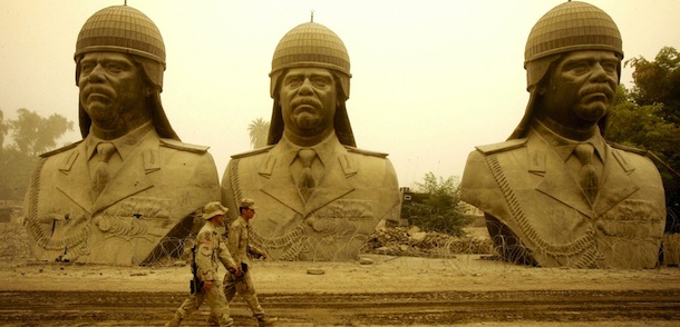 BAGHDAD, Iraq: In the midst of a storm that engulfed the Iraqi capitol, US army soldiers walk past the last remaining statues depicting the ousted dictator of Iraq, Saddam Hussein, at a US camp in Baghdad, 17 October, 2005. Saddam Hussein, the ousted dictator who delivered a brutal brand of justice to Iraqis during his 24-year reign, faces trial 20 October 2005 by an Iraqi tribunal which could sentence him to death if he is convicted. AFP PHOTO/DAVID FURST (Photo credit should read DAVID FURST/AFP/Getty Images)
