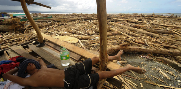 A boy sleeps on a shelter amongst logs that were washed up by typhoon Washi at Iligan City, southern Philippines on December 22, 2011. The bodies of victims of a devastating storm still litter the seas off the southern Philippines, officials said December 22 as fears mounted of disease outbreaks among survivors. AFP PHOTO/NOEL CELIS (Photo credit should read NOEL CELIS/AFP/Getty Images)
