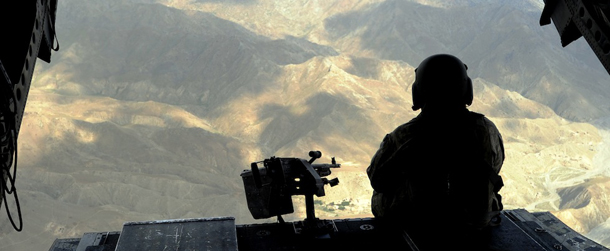 An US Chinook military helicopter personnel sits at the back of the chopper flying past mountains in Paktiya province, east of Afghanistan on July 1, 2011. The process of handing control from foreign to Afghan security forces and officials in seven areas of Afghanistan will start from late July, a senior official said June 30. AFP PHOTO/TED ALJIBE (Photo credit should read TED ALJIBE/AFP/Getty Images)