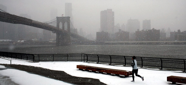 NEW YORK, NY - JANUARY 21: A woman runs by the Brooklyn Bridge in the morning snow on January 21, 2012 in the Brooklyn borough of New York City. After an unusually balmy early winter, New York City and much of the Northeast received its first snow storm of the year. Manhattan saw three to five inches of snow while areas north of the city received up to eight inches. (Photo by Spencer Platt/Getty Images)