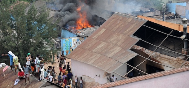 Sri Lankan prisoners climb onto nearby building roofs to get a view of a building set alight by rioting inmates on January 24, 2012. Prison guards opened fire on rioting inmates at Sri Lanka's main remand prison in the capital Colombo leaving 25 inmates and four guards wounded, officials said. The inmates, who were protesting over poor quality of food and overcrowding, also set fire to a kitchen and an administrative building. AFP PHOTO/Ishara S. KODIKARA (Photo credit should read Ishara S.KODIKARA/AFP/Getty Images)