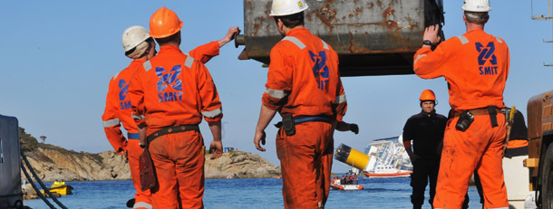 GIGLIO PORTO, ITALY - JANUARY 18: Rotterdam based SMIT and Livorno based NERI salvage workers prepare their work of diesel recovery from the the cruise ship Costa Concordia that lies stricken off the shore of the island of Giglio on January 18, 2012 in Giglio Porto, Italy. More than four thousand people were on board when the ship hit a rock off the Tuscan coast. The official death toll is now 11, with a further 24 people still missing. The rescue operation was temporarily suspended earlier due to the ship moving as it slowly sank further into the sea. (Photo by Laura Lezza/Getty Image)