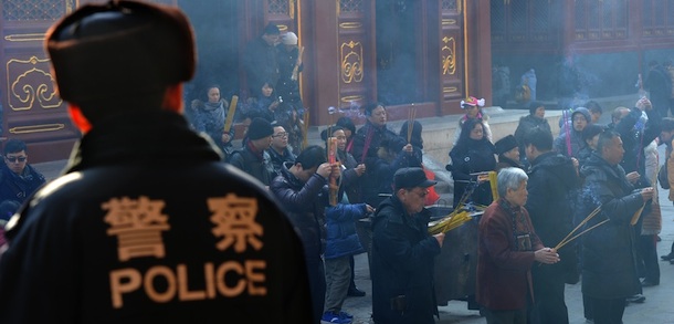 A Chinese policeman watches on as Buddhist worshippers (R) make wishes at the Tibetan Lama Temple in Beijing on January 25, 2012. China on January 25 confirmed police shot dead a "rioter" in a Tibetan-inhabited area, saying they had to use lethal force after a violent mob attacked them, state media said. AFP PHOTO/Mark RALSTON (Photo credit should read MARK RALSTON/AFP/Getty Images)