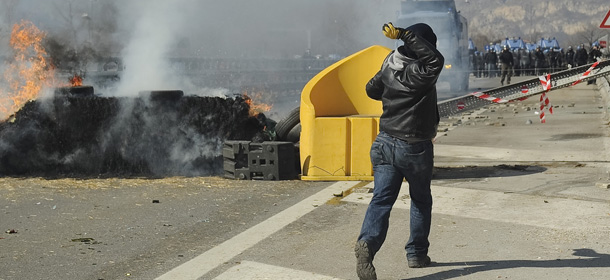An activist throws stones during a sit-in protest against the construction of a high-speed train line (TAV), near Chianocco, in North West Italy, Tuesday, Feb. 28, 2012. The construction of the fast train line, linking Turin to Lyon in France, has raised environmentalists' protests as well as that of the residents of the Susa valley contending that the new line is not an economic priority and that it will spoil the area. (AP Photo/Lapresse)