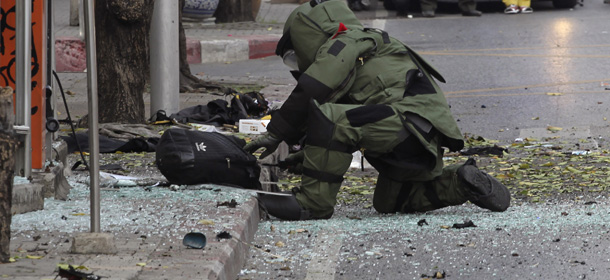 A Thai Explosive Ordnance Disposal (EOD) official examines a backpack that was left on the bomb site by a suspected bomber in Bangkok, Thailand Tuesday, Feb. 14, 2012. Thai police say two explosions have occurred in a Bangkok neighborhood. But it was not immediately clear what caused the blasts or wether there were an fatalities. (AP Photo/Apichart Weerawong)