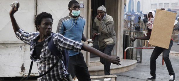 Anti-government protesters hurl rocks at police as they clash along a main street in central Dakar, Senegal Friday, Feb. 17, 2012. Anti-government protesters and police clashed for a third consecutive day Friday, engaging in running street battles of rock throwing and tear gas in the streets of Dakar's downtown Plateau neighborhood. Demonstrators are defying a government ban on protests to call for the departure of 85-year-old President Abdoulaye Wade, who is running for a third term in next week's election.(AP Photo/Rebecca Blackwell)