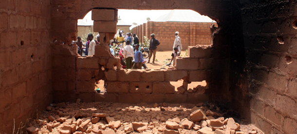 People stand outside an uncompleted building where tyres were burnt while kidnappers attempted to escape during the failed rescue operation of a pair of British and Italian hostages by Nigerian special forces at Mabera Area in Sokoto on March 9, 2012. Italy on Friday condemned as "inexplicable" Britain's failure to warn it ahead of time of an operation to rescue a pair of British and Italian hostages in Nigeria that resulted in their deaths. "The behaviour of the British government, which did not inform or consult with Italy on the operation that it was planning, really is inexplicable," President Giorgio Napolitano told reporters a day after the assault. AFP PHOTO / EMMANUEL AREWA (Photo credit should read EMMANUEL AREWA/AFP/Getty Images)