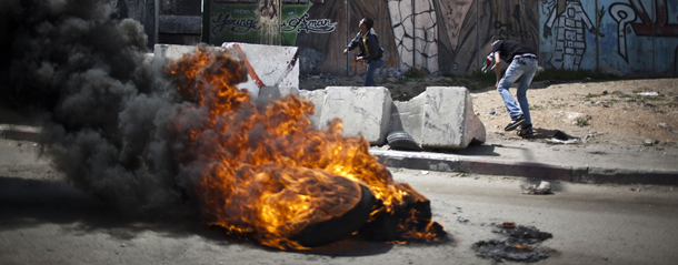 KALANDIA, WEST BANK - MARCH 30: Protesters burn tiers during clashes near the Kalandia military check point on March 30, 2012 in the Palestinian village of Kalandia, West Bank. The clashes coincided with Land Day, which began in 1976, marking the day Israeli forces killed six Palestinians during a protest against Israeli occupation of what Palestinians consider to be their land. Palestinians around the world are commemorating Land Day with protests and demonstrations including an annual march to Jerusalem. (Photo by Ilia Yefimovich/Getty Images)