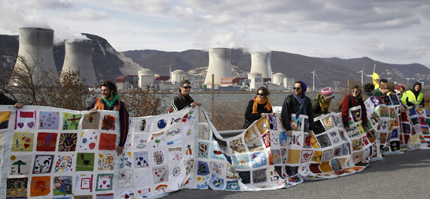Anti-nuclear supporters and activists demonstrate in front of the Cruas nuclear power plant in La Coucourde, south France, Sunday, March 11, 2012. They tried to form a 235km human chain from Lyon to Avignon, a region with a high number of nuclear plants, to commemorate the Fukushima nuclear accident's first anniversary. (AP Photo/Laurent Cipriani)