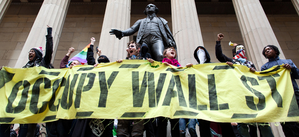 Occupy Wall Street demonstrators stand and cheer in front of the George Washington statue on Wall Street as they celebrate the protest's sixth month, Saturday, March 17, 2012, in New York. With the city's attention focused on the huge St. Patrick's Day Parade many blocks uptown, the Occupy rally at Zuccotti Park on Saturday drew a far smaller crowd than the demonstrations seen in the city when the movement was at its peak in the fall. A couple hundred people attended. (AP Photo/John Minchillo)