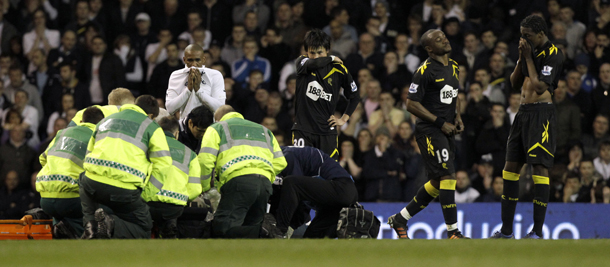 Bolton Wanderers' Fabrice Muamba is obscured by medical staff trying to resuscitate him after collapsing watched by his teammates Ryo Miyaichi, third right, Nigel Reo-Coker, second right, Dedryck Boyata, right, and Tottenham Hotspur's Jermain Defoe, left white shirt, during the English FA Cup quarterfinal soccer match between Tottenham Hotspur and Bolton Wanderers at White Hart Lane stadium in London, Saturday, March 17, 2012. Bolton midfielder Fabrice Muamba has been carried off the field at Tottenham after medics appeared to be trying to resuscitate him during an FA Cup quarterfinal that was abandoned. Muamba went to the ground in the 41st minute with no players around him and the game was immediately stopped. (AP Photo/Matt Dunham)