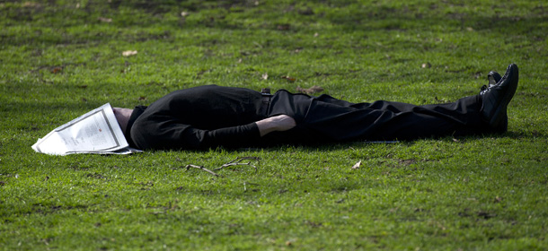 A man sleeps with a newspaper on his face in the grass enjoying the warm weather in a park in central London on March 15, 2012. AFP PHOTO / CARL COURT (Photo credit should read CARL COURT/AFP/Getty Images)