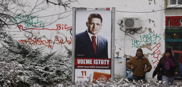 Residents walk past an election poster with the chairman of the SMER-Social Democracy party Robert Fico in Bratislava, Slovakia, Thursday, March 8, 2012. Slovakia is holding early general elections on Saturday, March 10, 2012. (AP Photo/Petr David Josek)