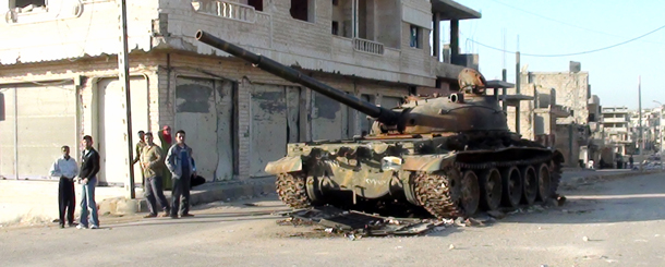 Syrians stand next to an abandoned army tank in the city of Rastan, near the flashpoint city of Homs, on March 9, 2012. AFP PHOTO/STR (Photo credit should read -/AFP/Getty Images)