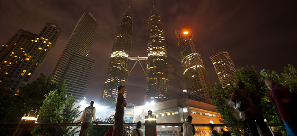 People gather in front of Malaysia's iconic Patronas Twin Towers (C) as they stand unlit during Earth Hour in Kuala Lumpur on March 31, 2012. Millions of people were expected to switch off their lights for Earth Hour on March 31, in a global effort to raise awareness about climate change. Since it began in Sydney in 2007, Earth Hour has grown to become what environmental group WWF says is the world's largest demonstration of support for action on carbon pollution. AFP PHOTO/Saeed KHAN (Photo credit should read SAEED KHAN/AFP/Getty Images)