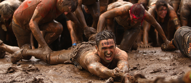 PHILLIP ISLAND, AUSTRALIA - APRIL 01: Competitors help pull each other up a mud hill during the 2012 Toughmudder on April 1, 2012 in Phillip Island, Australia. (Photo by Quinn Rooney/Getty Images)