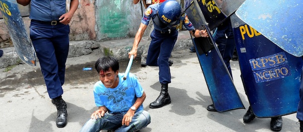 A policeman hits a resident during a demolition order on informal settlers' homes at Paranaque city, south of Manila on April 23, 2012. One person was killed and at least six were injured as heavily-armed riot police clashed with hundreds of squatters in a suburb of the Philippine capital, police said. The fatality occurred as squatters blocked a road in the residential suburb of Paranaque, hurling large stones at police, armed with shields and truncheons, who were trying to disperse them. AFP PHOTO/NOEL CELIS (Photo credit should read NOEL CELIS/AFP/Getty Images)