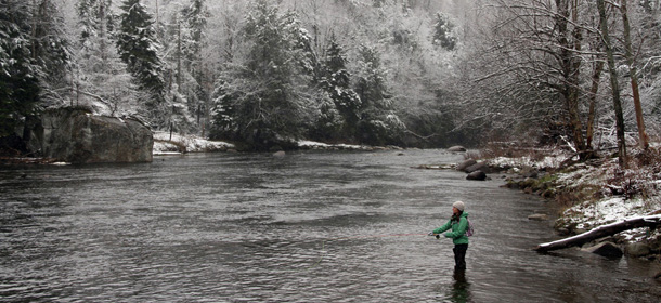 A woman fishes on the West Branch of the AuSable River in Wilmington, N.Y., after a snowfall on Sunday, April 22, 2012. A spring nor'easter along the East Coast on Sunday is expected to bring rain and heavy winds and even snow in some places as it strengthens into early Monday, a punctuation to a relatively dry stretch of weather for the Northeast. (AP Photo/Adirondack Daily Enterprise, Mike Lynch)