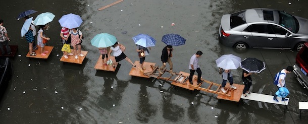 In this picture taken on May 29, 2012, residents cross a flooded street on a row of tables in Wuhan, central China's Hubei province. China is hit by big summer rainfalls every year, as heavy downpours across large swathes of the country trigger flooding, landslides and other rain-related disasters. CHINA OUT AFP PHOTO (Photo credit should read AFP/AFP/GettyImages)