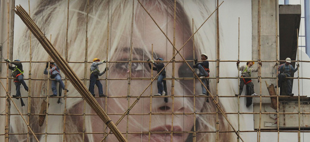 Workers climb on scaffolding over a billboard poster on the side of a building in Hong Kong on February 17, 2011. A global survey has found that luxury residential rents in Hong Kong surpassed Tokyo with a three-bedroom apartment in the Chinese city's glitzy Peak neighbourhood costing an average 16,700 USD a month, about 30 percent more than Tokyo. AFP PHOTO / ED JONES (Photo credit should read Ed Jones/AFP/Getty Images)