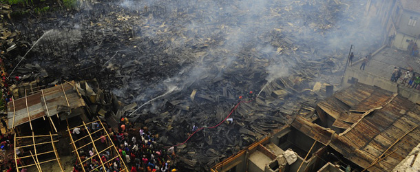 The remnants of houses smoulder following a blaze at a slum in Dhaka on May 16, 2012. Over a thousand homes burnt down as a devastating blaze raged through the slum. AFP PHOTO/ Munir uz ZAMAN (Photo credit should read MUNIR UZ ZAMAN/AFP/GettyImages)