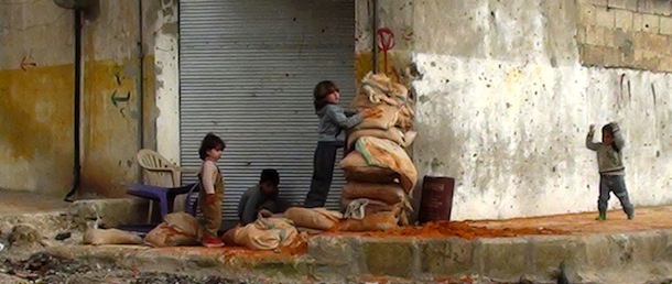 Syrian children hide behind sand bags on the street in the central town of Rastan, near Homs, on March 13, 2012. UN-Arab League envoy Kofi Annan, who met with President Bashar al-Assad in Damascus on March 10, said he had made "concrete" proposals to the Syrian leader on ways to halt the attacks and secure humanitarian access to cities where the United Nations says thousands have been killed in the past year. AFP PHOTO/STR (Photo credit should read STR/AFP/Getty Images)