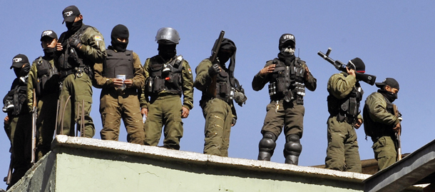 Armed mutinied policemen stand on the roof of a police headquarters in La Paz, on June 23, 2012 during a police strike demanding a salary increase. Bolivian government officials and police officers demanding better pay planned a new round of talks Saturday after failing to reach agreement amid a nationwide mutiny. AFP/PHOTO/Aizar Raldes (Photo credit should read AIZAR RALDES/AFP/GettyImages)