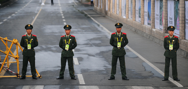 Paramilitary policemen a roadblock leading to Olympic Torch Relay festivities within restricted roads at People's Square on June 17, 2008 in Urumqi, capital of China's northwest Xinjiang Uighur Autonomous Region. China kicked off the Olympic torch relay's sensitive leg through Xinjiang, its largely Muslim western region where Beijing acknowledges there are ethnic tensions leaving Urumqi largely shut down with police checkpoints restricting movement throughout the normally bustling city as the relay got underway. AFP PHOTO/Frederic J. BROWN (Photo credit should read FREDERIC J. BROWN/AFP/Getty Images)