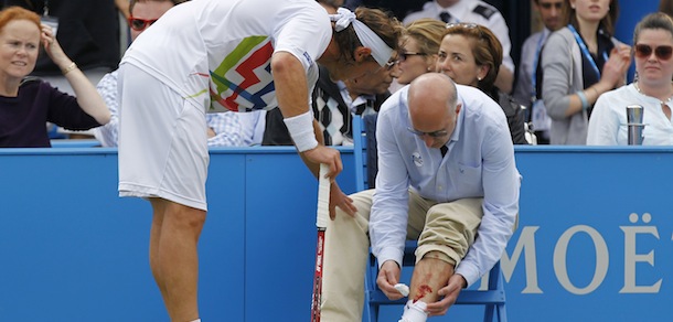Argentina's David Nalbandian, left, checks on the line judge after causing an injury to him, for which he was disqualified, during the Queen's Club grass court championships final tennis match against Croatia's Marin Cilic, London, Sunday, June 17, 2012. Nalbandian kicked the small barrier surrounding the line judge in anger. A piece of the barrier then hit the line judge, causing bleeding on his left shin. (AP Photo/Sang Tan)