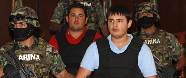 ** ADDS LAST THREE SENTENCES REGARDING IDENTITY OF SUSPECT ** Mexican marines escort who authorities identify as Jesus Alfredo Guzman Salazar, 26, behind center, and Kevin Beltran Rios during their presentation to the media in Mexico City, Thursday, June 21, 2012. Guzman Salazar, 26, is allegedly one of the sons of Mexico's most-wanted drug kingpin, Joaquin "El Chapo" Guzman Loera, leader of the powerful Sinaloa cartel. Karla Pacheco, the wife of the man shown to the press, says they got the wrong man, saying he is really Felix Beltran Leon, the 23-year-old father of a toddler who works with his mother-in-law at a used car dealership. Pacheco said the other man is her husband's half-brother, 19-year-old Kevin Daniel Beltran Rios. The possible misidentification could be embarrassing for both Mexico and the U.S. in the cat-and-mouse game they are playing with "El Chapo," who has been on the run since escaping from a Mexican prison in a laundry cart in 2001. (AP Photo/Eduardo Verdugo)