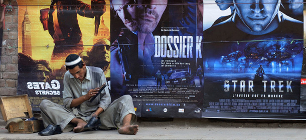 A Pakistani cobbler shines a pair of shoes in front of the western film posters on a roadside in Lahore on May 14, 2010. Pakistan approached the International Monetary Fund (IMF) in 2008 for a rescue package as it grappled with a 30-year high inflation rate and fast-depleting reserves that were barely enough to cover nine weeks of import bills. The IMF is set to approve a 11.35 billion-dollar loan later this month. AFP PHOTO/ARIF ALI (Photo credit should read Arif Ali/AFP/Getty Images)
