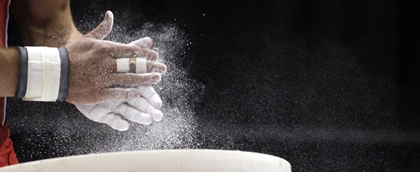 Lo statunitense Sam Mikulak si mette del gesso sulle mani prima di iniziare una prova dei campionati statunitensi di ginnastica. 
(AP Photo/Jeff Roberson)