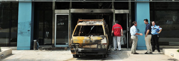 Investigators work near the mini-van used by attackers at entrance to the Microsoft office in an Athens northern suburb on June 27, 2012. Attackers targeted the Microsoft main office in the Greek capital in a pre-dawn arson attack Wednesday, smashing the entrance with a mini-van and setting off gas canisters, police said.Anti-terrorist police were investigating, and authorities did not rule out an extremist group was behind the attack, which caused no casualties. AFP PHOTO / LOUISA GOULIAMAKI (Photo credit should read LOUISA GOULIAMAKI/AFP/GettyImages)