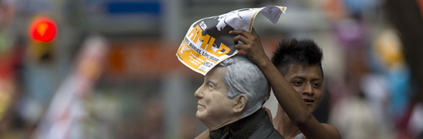 Supporters of Andres Manuel Lopez Obrador, presidential candidate for the Democratic Revolution Party (PRD) place a mask with the likeness of Lopez Obrador on a statue as they head towards the main Zocalo plaza to participate in Lopez Obrador's final campaign closing rally in Mexico City, Mexico, Wednesday, June 27, 2012. Next July 1, Mexico will hold presidential elections. (AP Photo/Dario Lopez-Mills)