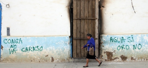 A woman walks past graffitis reading "Water yes, Gold no!" and "No to Conga, damn it", in the Andean town of Celendin, Cajamarca, Peru on July 5, 2012, after clashes between the police and people protesting against the Conga mining project. A total of five civilians were killed and more than twenty were wounded in Cajamarca after two days of protests against the Conga mining project, while police forces deny the use of guns in their crowd control actions in the area. AFP PHOTO/STR (Photo credit should read STR/AFP/GettyImages)